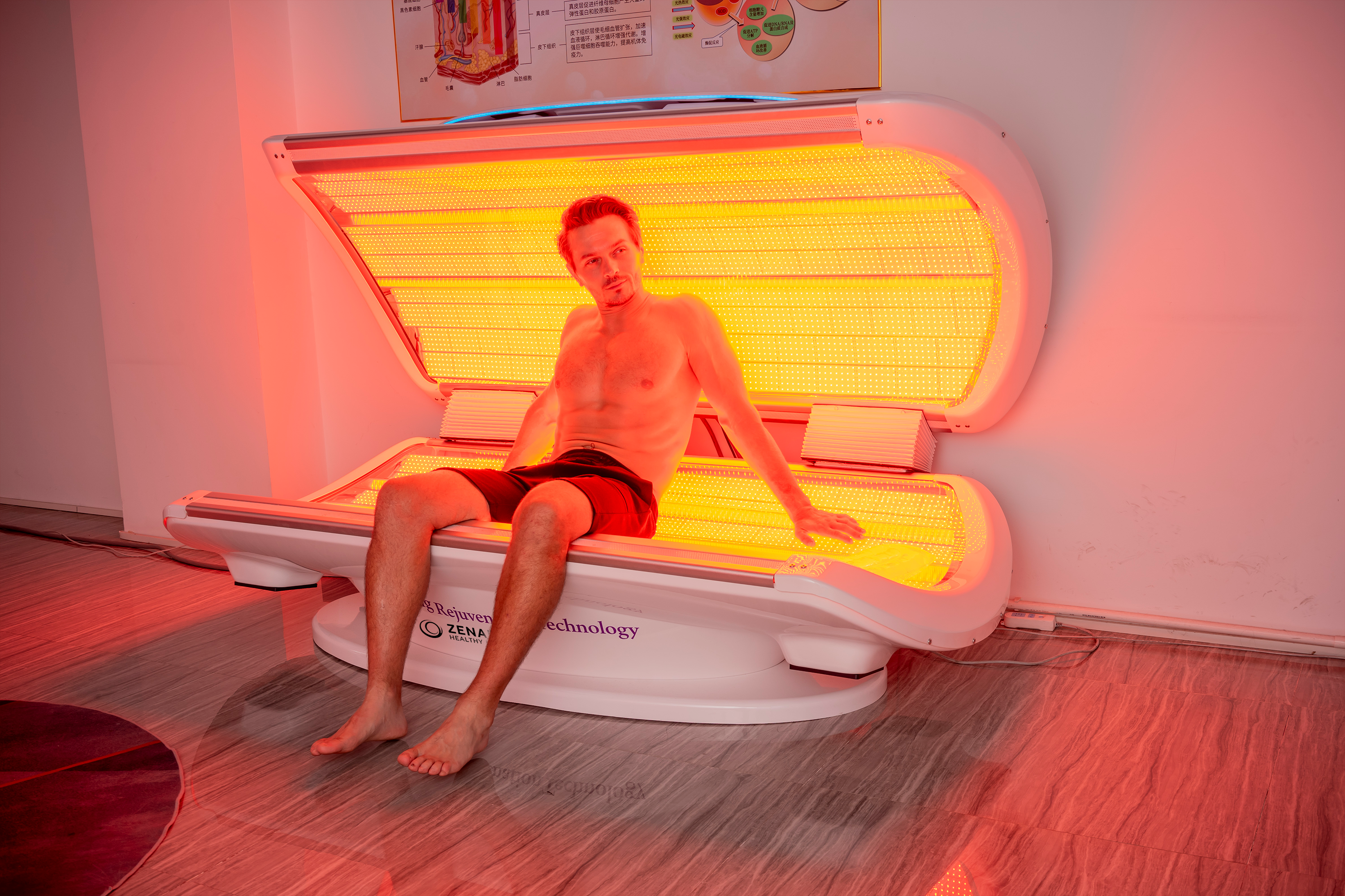 Man sitting inside the Zenapura MaxiLUX Red Light Therapy Bed during a session, showing full-body red and near infrared light therapy for skin rejuvenation, pain relief, and muscle recovery.